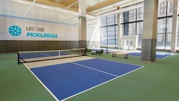 A pickleball court is set up indoors with a net and paddles at SKY Apartments, New York, 10036